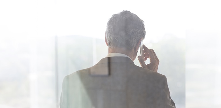 Photo d’un homme vu de dos qui parle au cellulaire dans un édifice à bureaux
