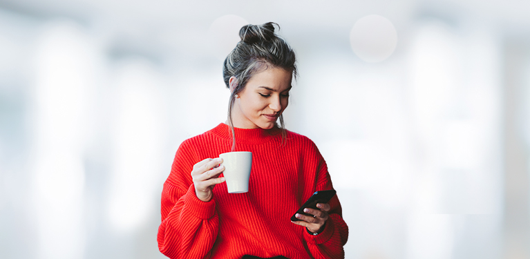 Photo d’une femme qui boit un café en consultant son cellulaire 