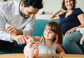 Photo d'un couple avec leur fille en train de jouer avec une tirelire