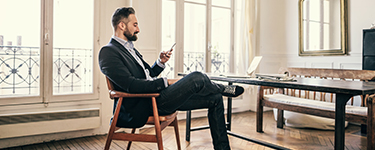 Homme en veston assis à un bureau regarde son téléphone