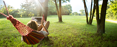 Femme navigue sur sa tablette dans un hamac