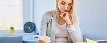 Femme réfléchit en regardant ses factures