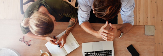 Couple qui discute avec cahier de notes et ordinateur