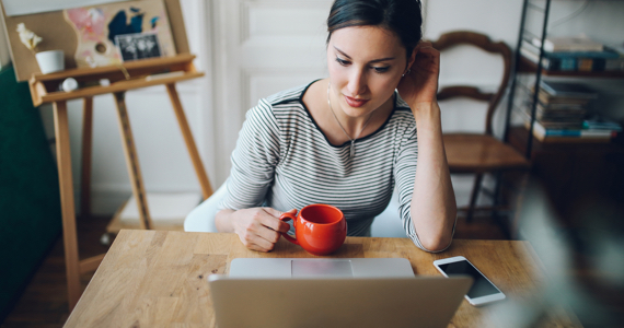 Jeune femme assise à une table regarde son ordinateur