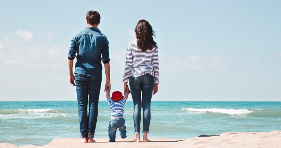 Parents tiennent bébé par la main sur le bord de la mer