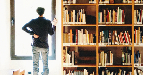 Homme regarde par la fenêtre près d'une bibliothèque