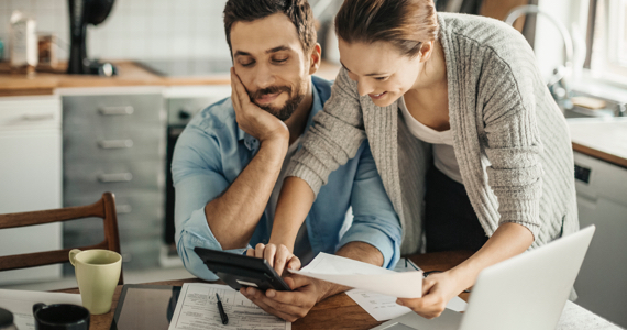 Couple souriant regarde des documents et une tablette