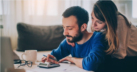 Photo d'un couple à une table de cuisine avec une calculatrice