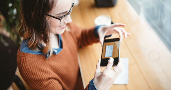 Jeune femme prend une photo d’un chèque avec son téléphone