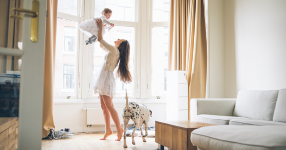 Femme joyeuse soulève son bébé dans les airs dans son salon