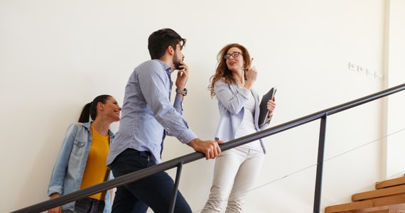 Photo d'un couple discutant avec une agente immobilière dans un escalier