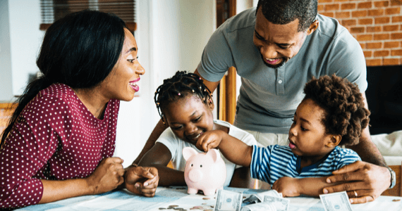 Photo de deux parents avec leurs deux enfants jouant avec une tirelire 