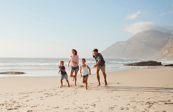 Photo de parents et enfants souriants qui courent sur une plage