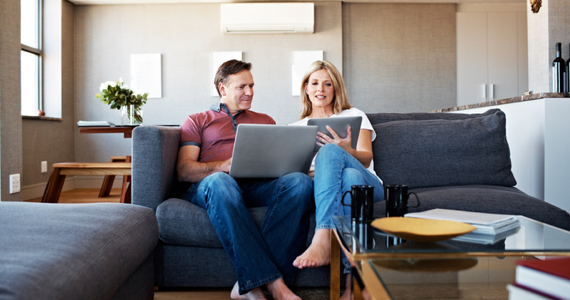 Femme montre sa tablette à son conjoint sur leur divan