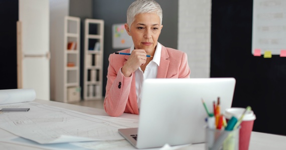 Femme aux cheveux blancs à son bureau regarde son ordinateur