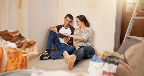 Jeune couple assis par terre dans une maison en travaux