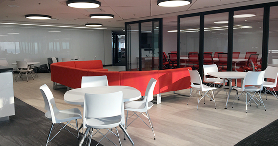 Vue sur un étage de bureaux avec des tables, un grand canapé et une salle de réunion