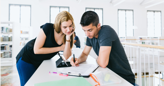 Jeune étudiante et jeune étudiant sont penchés sur un document