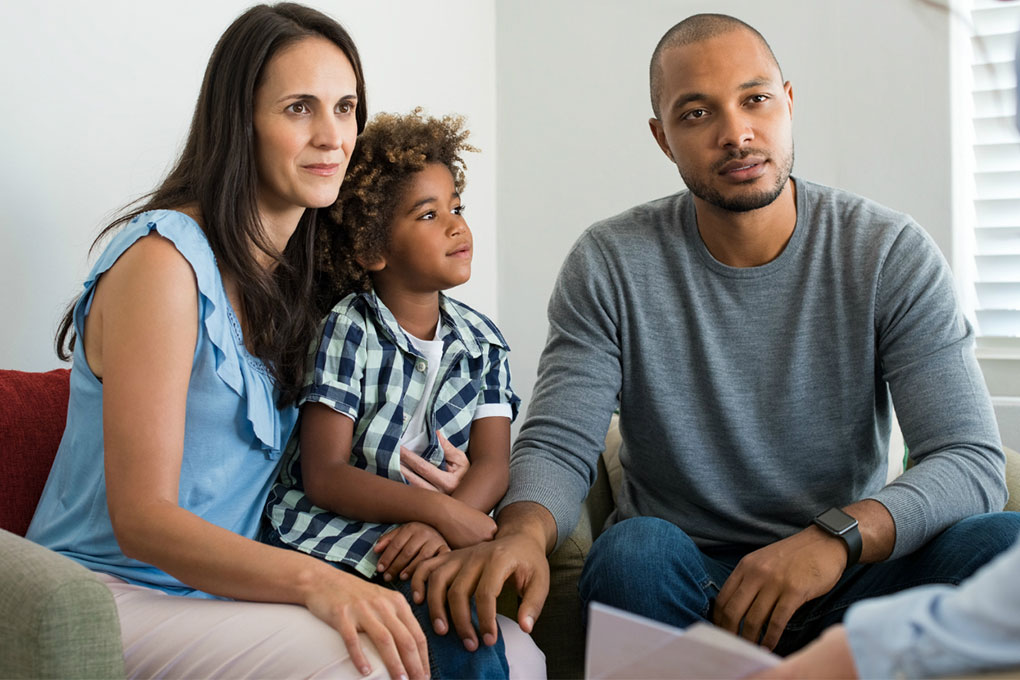 Jeunes parents accompagnés de leur enfant, discutant de fiducie testamentaire avec un professionnel.  