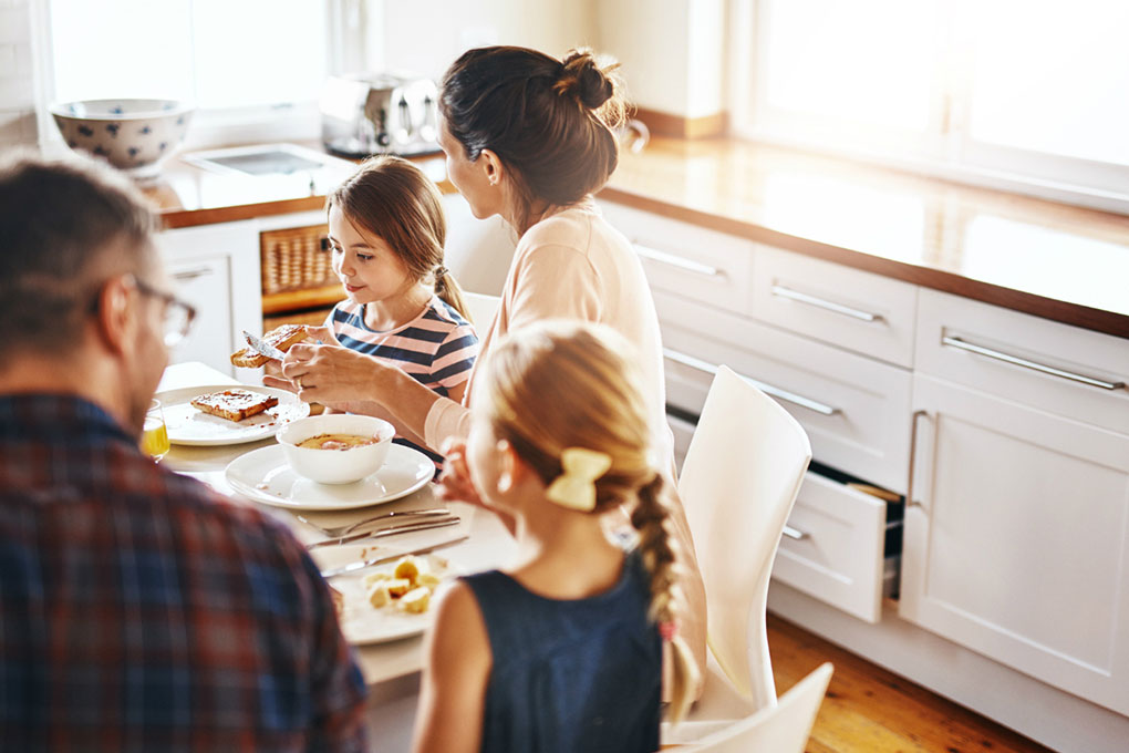 Un couple déjeune dans la cuisine avec leurs enfants