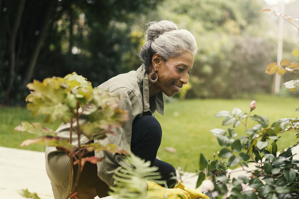 Dame réfléchissant à sa retraite tout en jardinant. 