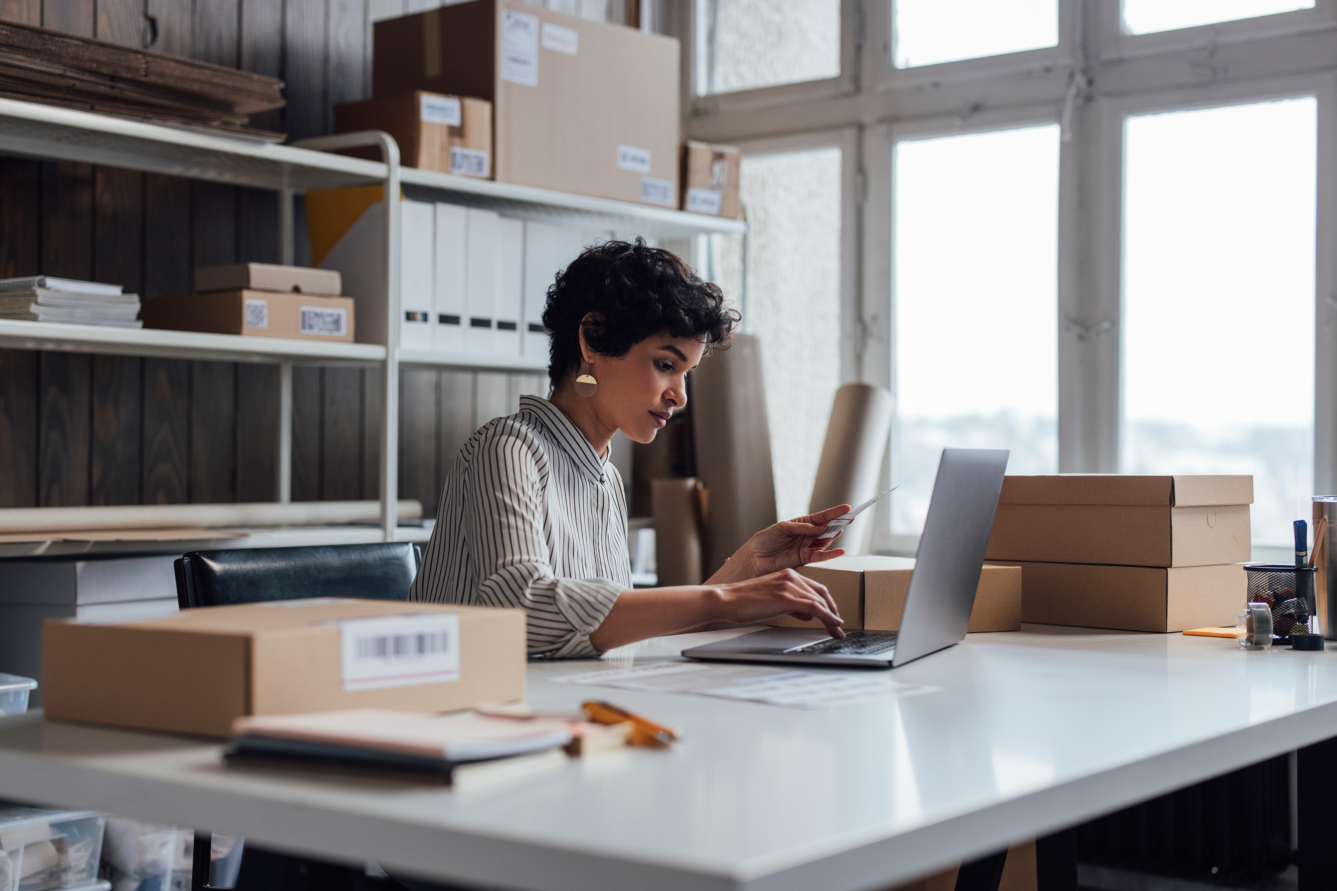 Personne travaillant sur un ordinateur portable à un bureau avec des boîtes en carton. 