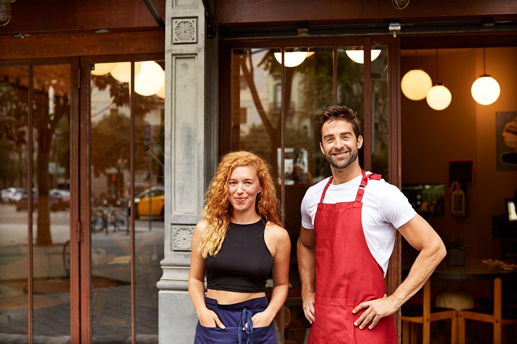 Des propriétaires de franchise posent avec le sourire devant leur commerce.