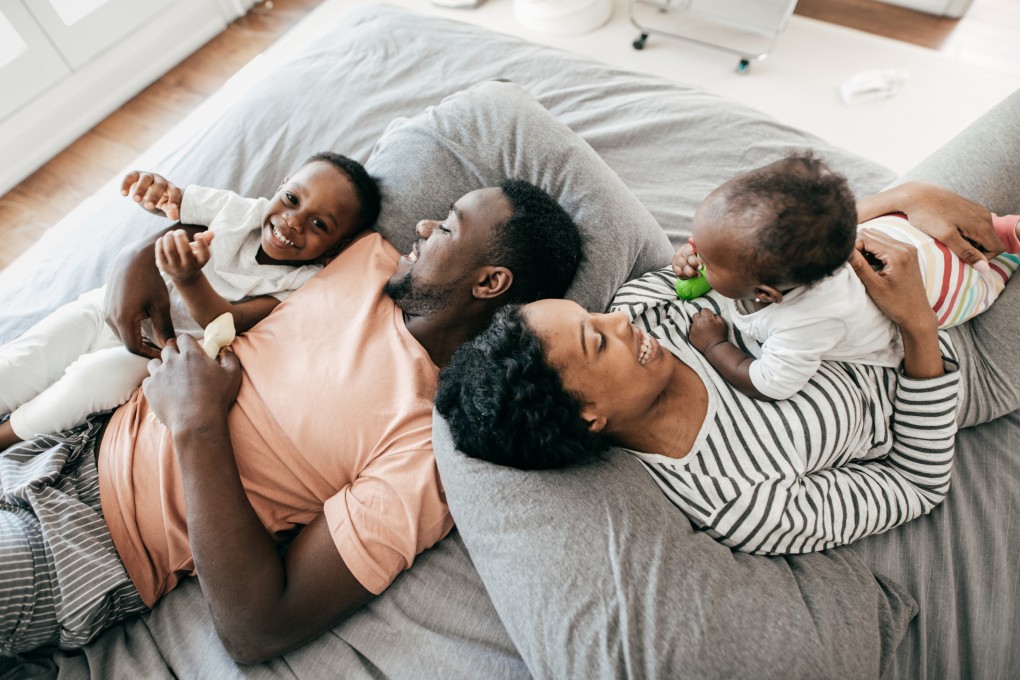 Une femme enceinte et son conjointe jouent au salon avec leur enfant.