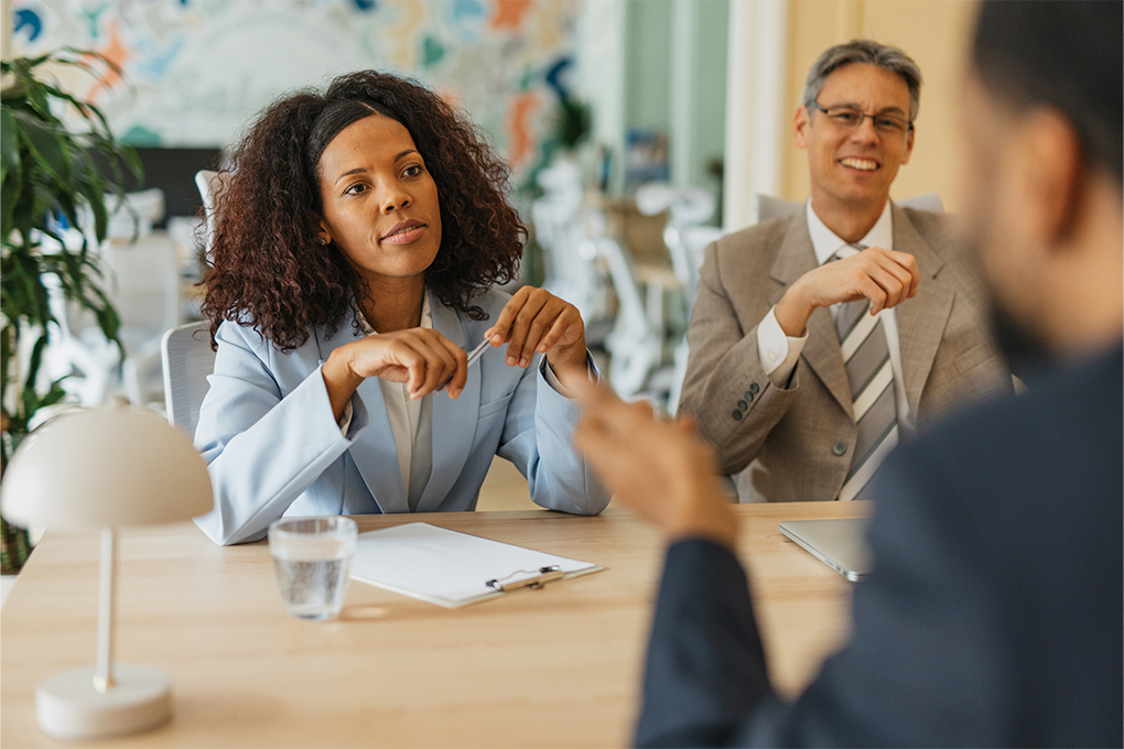 Discussion entre trois personnes autour d’une table dans un bureau.
