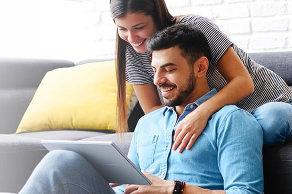 Photo d'un couple assis sur un canapé et qui regarde une tablette