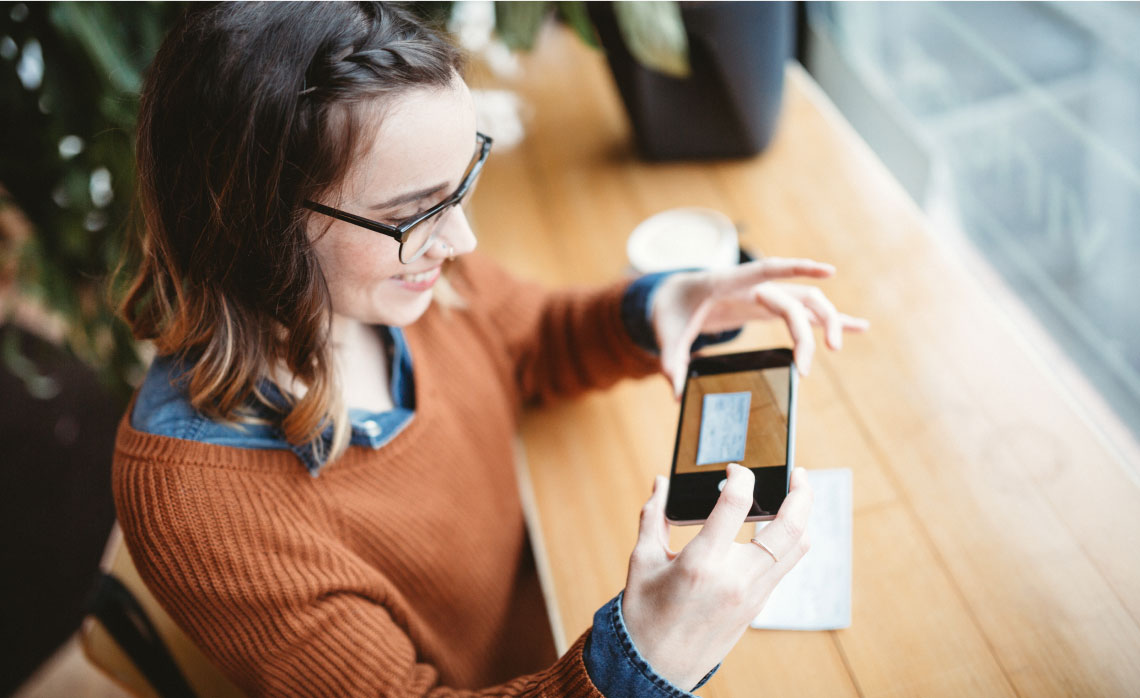 Photo d’une femme prenant une photo d’un chèque avec son cellulaire