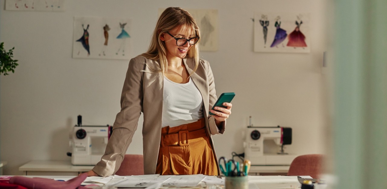 Photo d’une personne souriante qui consulte son téléphone cellulaire dans son bureau 