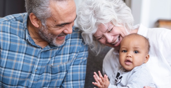 Image d’un couple âgé souriant en tenant un bébé