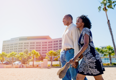 Photo d’un couple marchant sur une plage près d’un immeuble à condos en Floride