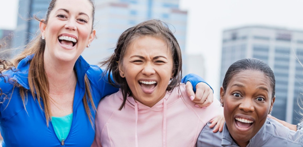 Photo de quatre personnes souriant en se tenant par les épaules