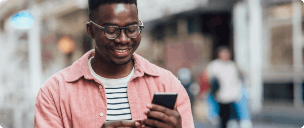 Photo d'une personne jeune en train de sourire en regardant son cellulaire