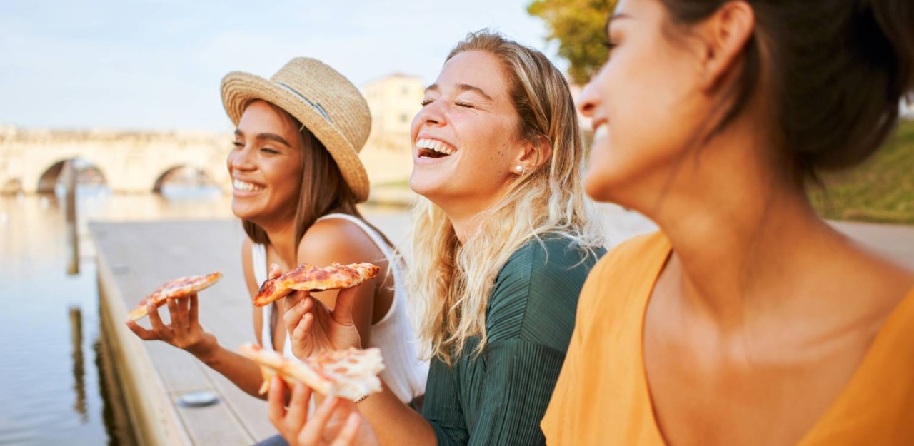 Photo d’un groupe de trois personnes en train de manger et de rire