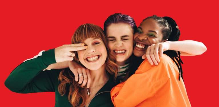 Photo de trois jeunes qui se serrent dans leurs bras en souriant 
