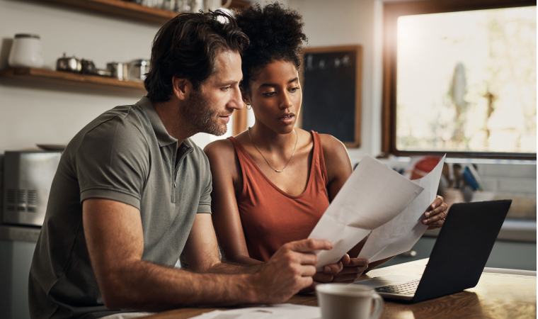 Photo d’un couple consultant des documents dans leur cuisine