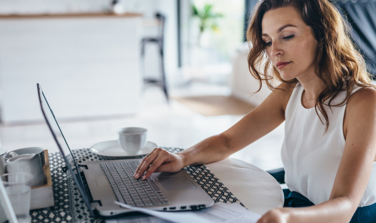 Photo d’une femme consultant un document et son ordinateur dans un café éclairé