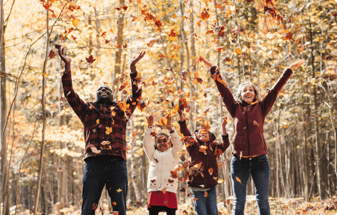 Photo d’une famille jouant avec des feuilles dans la forêt