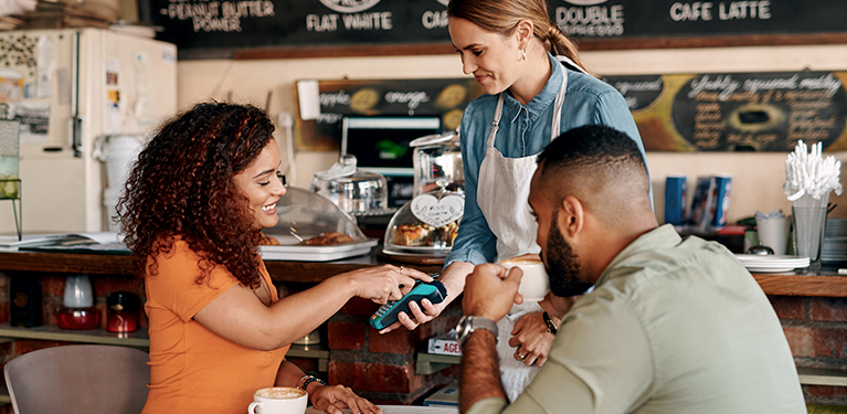 photo d'une femme qui paye sa facture au restaurant avec son cellulaire.