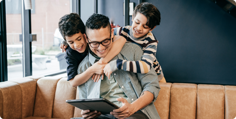 Photo d’un parent assis sur un sofa et jouant avec ses deux enfants