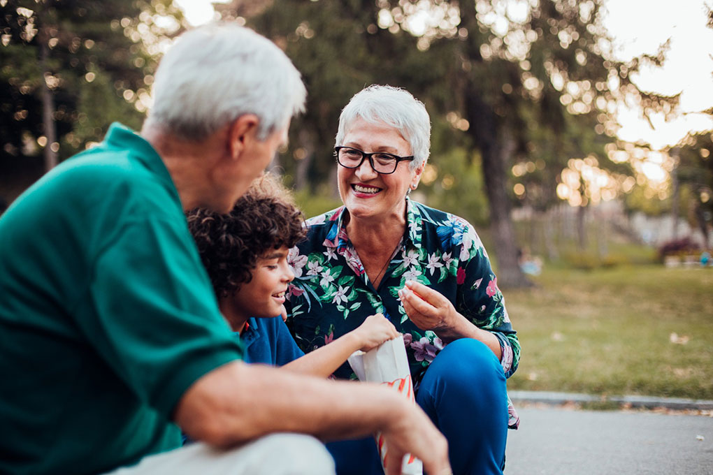 Photo de deux grands-parents souriants entourant leur petit-fils