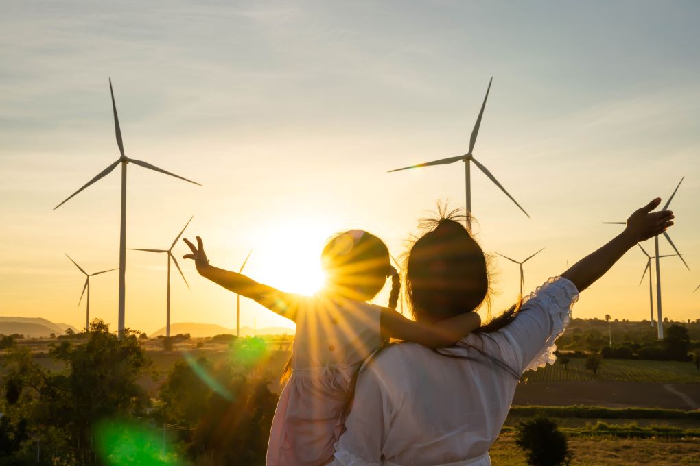 Photo de deux personnes se tiennent ensemble devant des éoliennes avec coucher de soleil 