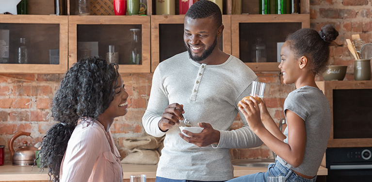 Photo d’un couple et d’un enfant souriants qui discutent dans une cuisine