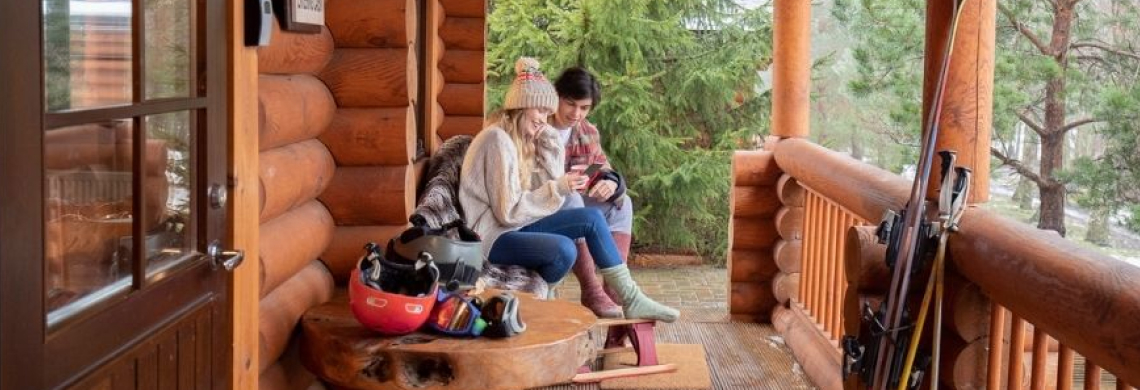 Photo de deux personnes assises sur un balcon de chalet 