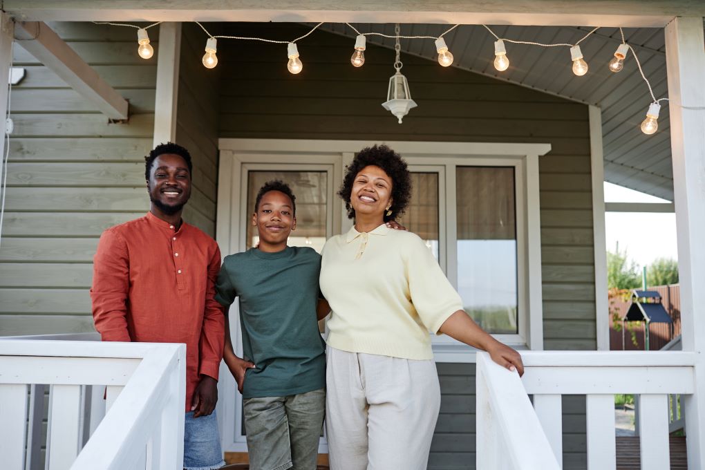 Photo d’un couple avec un enfant devant une maison