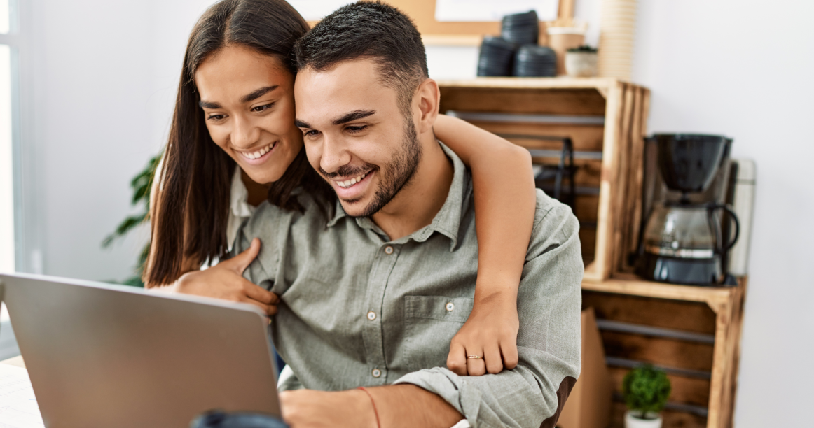 Photo d’un couple souriant devant un ordinateur